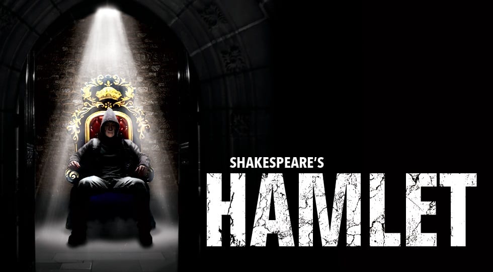 Poster for Hamlet, featuring a man in a hoodie sitting on a throne under a spotlight