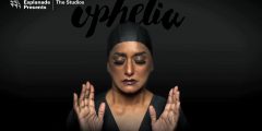 An image of a woman, wearing a swimming cap, holding up her hands with her eyes closed, and the word 'ophelia' above.