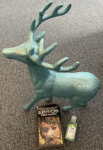 Teal Deer with copy of Survivors novel and a hand gel.