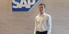 Matthew Thompson (BSc Management) in fronT of SAP logo