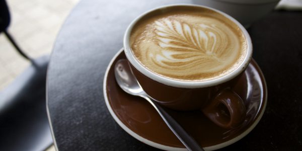 Photographer shot of a cup of coffee with a leaf shape drizzled into the coffee