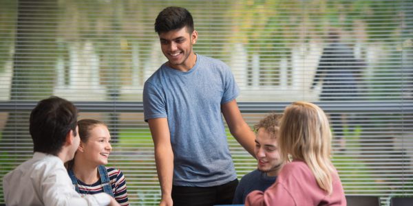 Man standing up, smiling in a group conversation