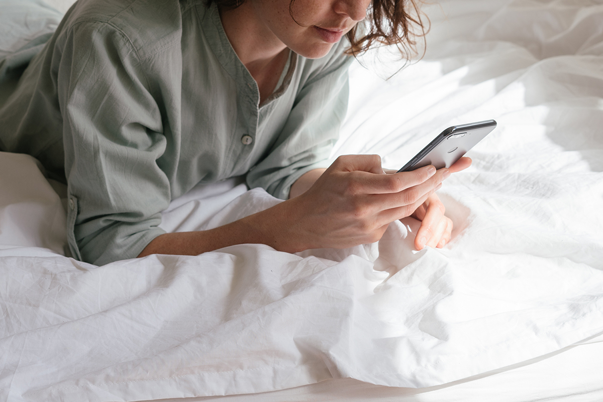 Student using smartphone in bed