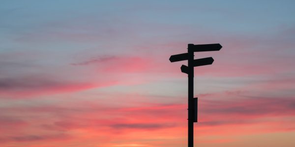 Signpost with diverging directions with a sunset background