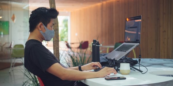 Man wearing mask using a laptop