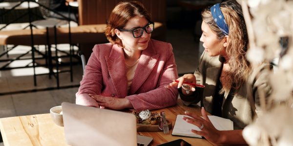 Two females sat together talking with a laptop.