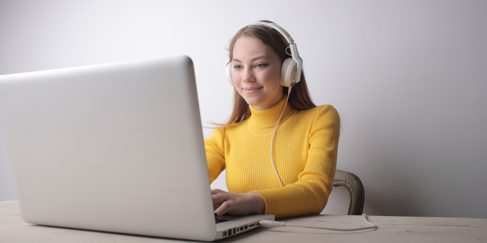 Young woman sat working on her laptop with headphones on.