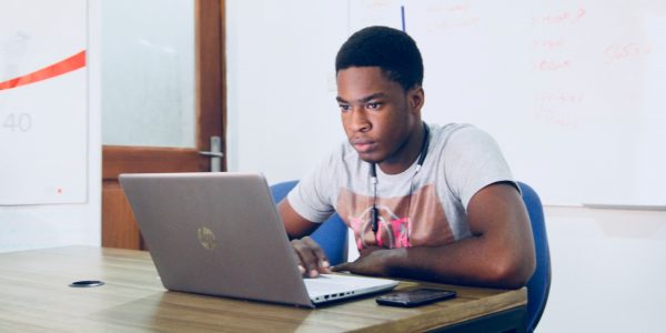 young male student looking at laptop.