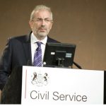 Man in suit presenting with Civil Service logo in front