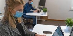 Woman sat in an office with a mask on