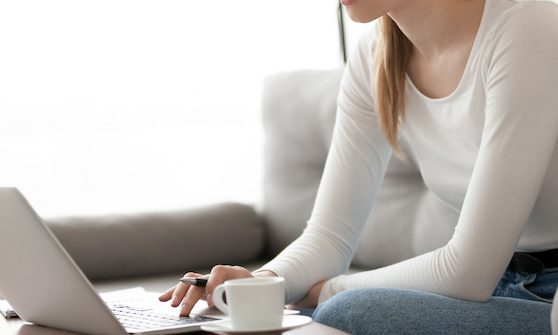 Young woman freelancer using laptop working online making notes