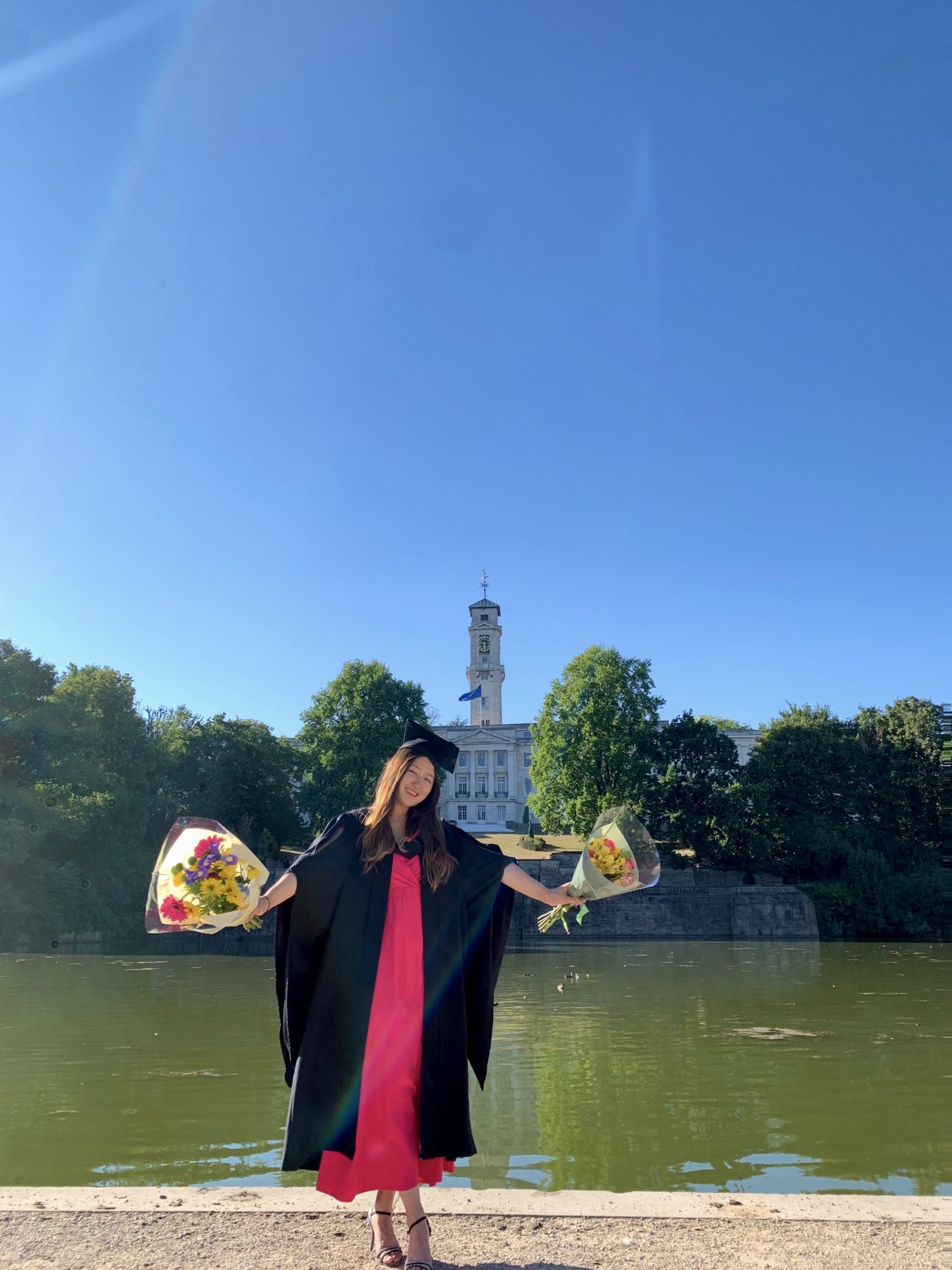 Graduate, Saejin Lee, holding flowers in graduation gown