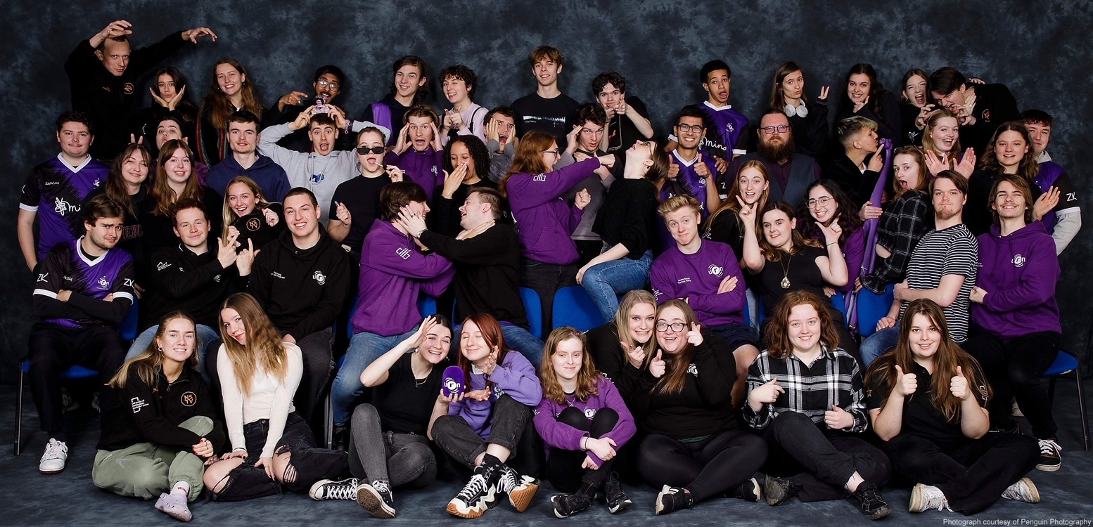 A large group of students from University Nottingham are gathered dressed in the station's colours (black and purple clothing)