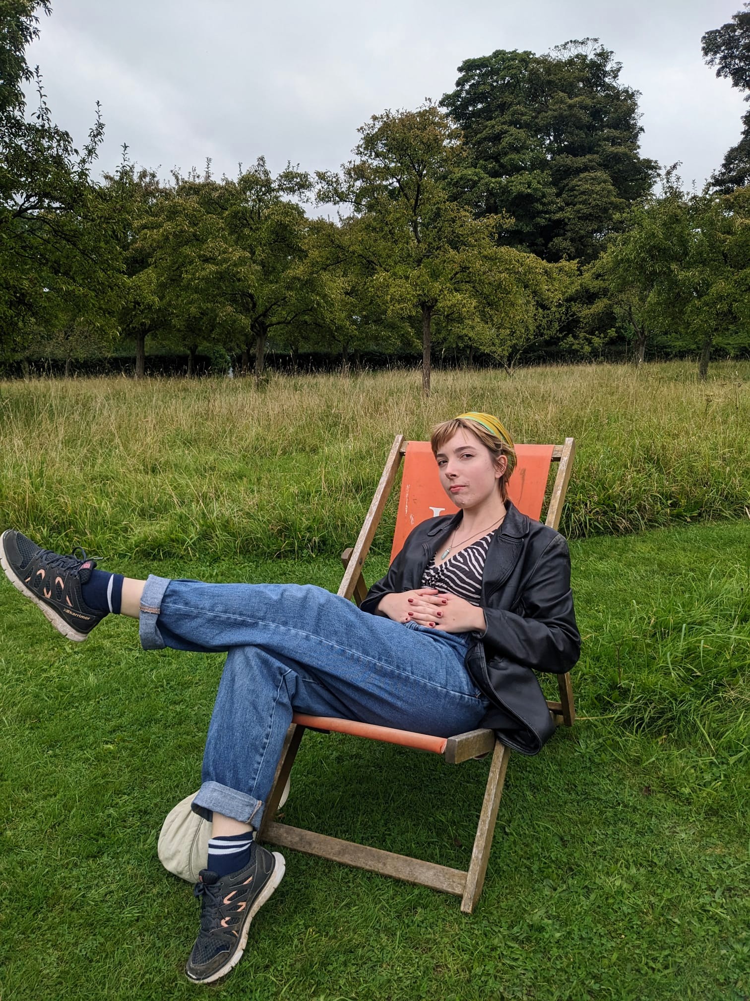 A picture of a girl sat in a chair in a field