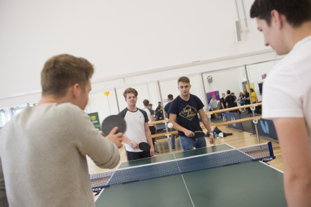 Four males playing table tennis, two males on each side
