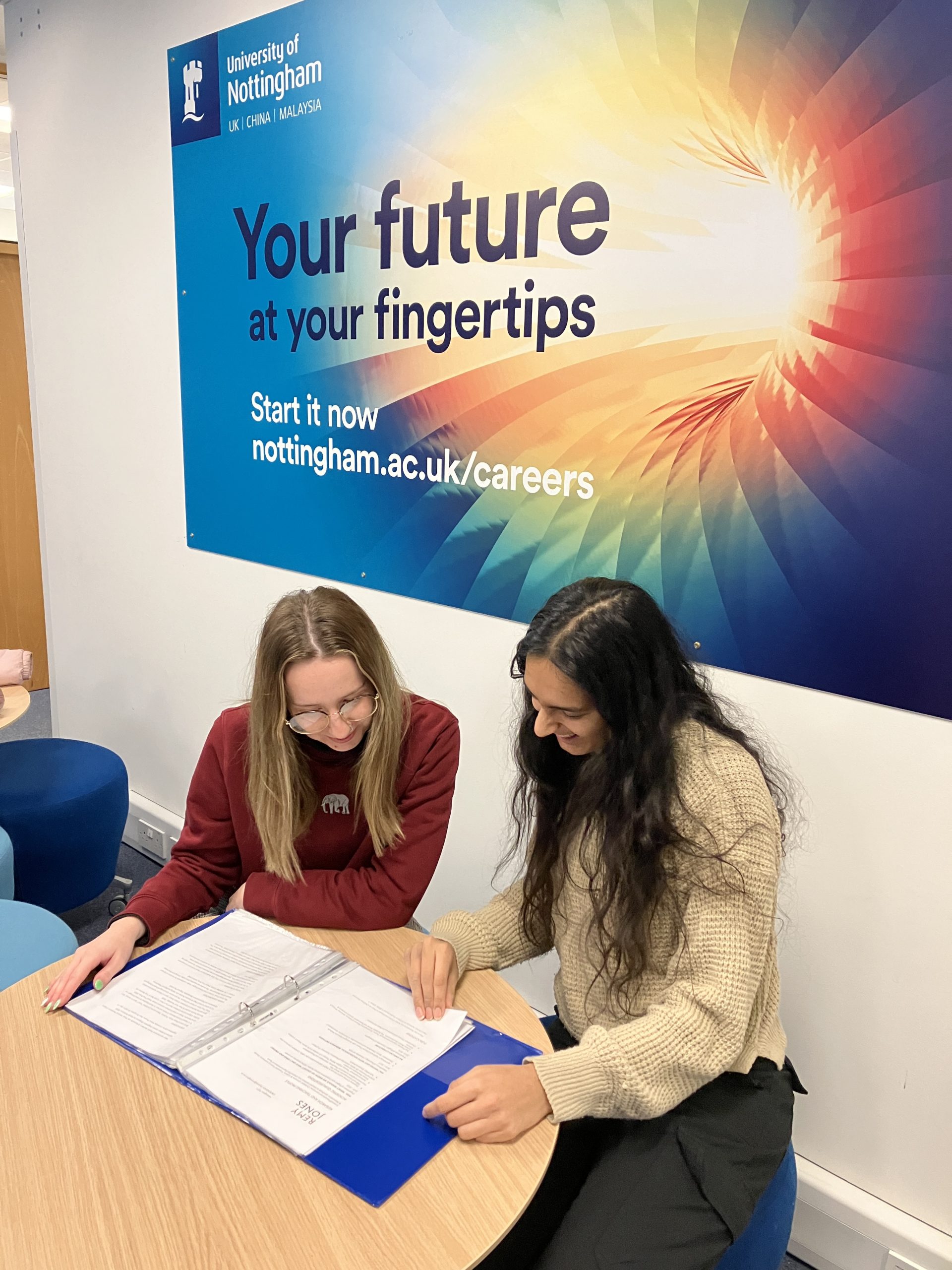 An image of two people looking at a folder together in a careers office