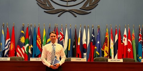 Jack Crawford at the UNI standing in front of the UN logo and national flags