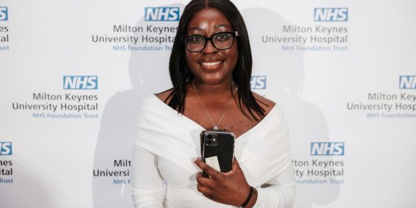 Lilly Koranteng standing in front of a board with NHS Milton Keynes University Hospital