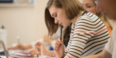 Female student looking down at a table with a laptopopen