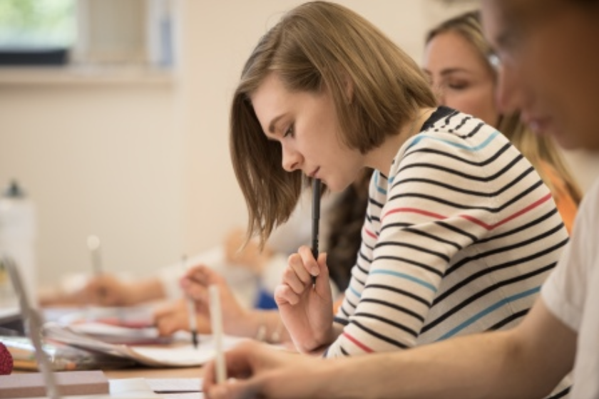 Female student looking down at a table with a laptopopen