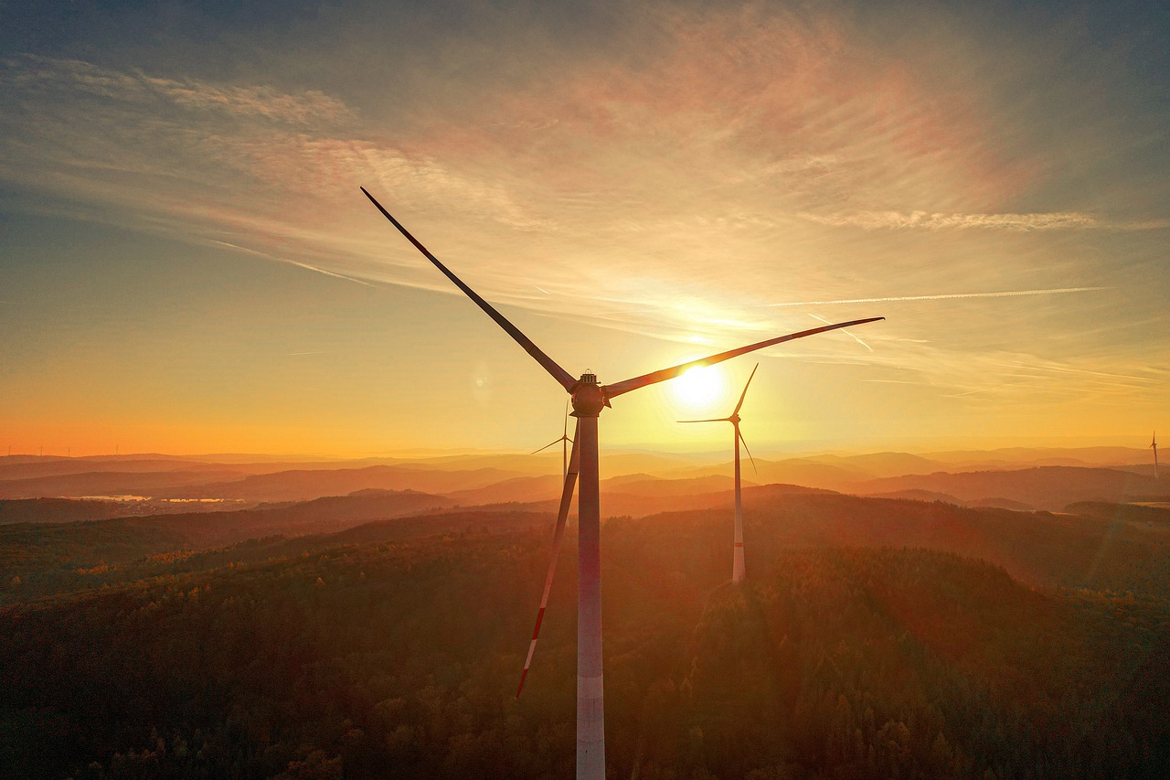 Wind powered windmills in a landscape showing a sunset