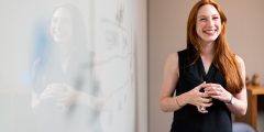 Woman standing next to whiteboard smiling