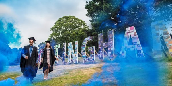 Two graduates walking on the grass infant of Nottingham Sign