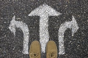 Two feet standing on a concrete path with arrows pointing in three possible directions