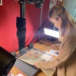 Photograph of a student using the copystand and camera to photograph a newspaper