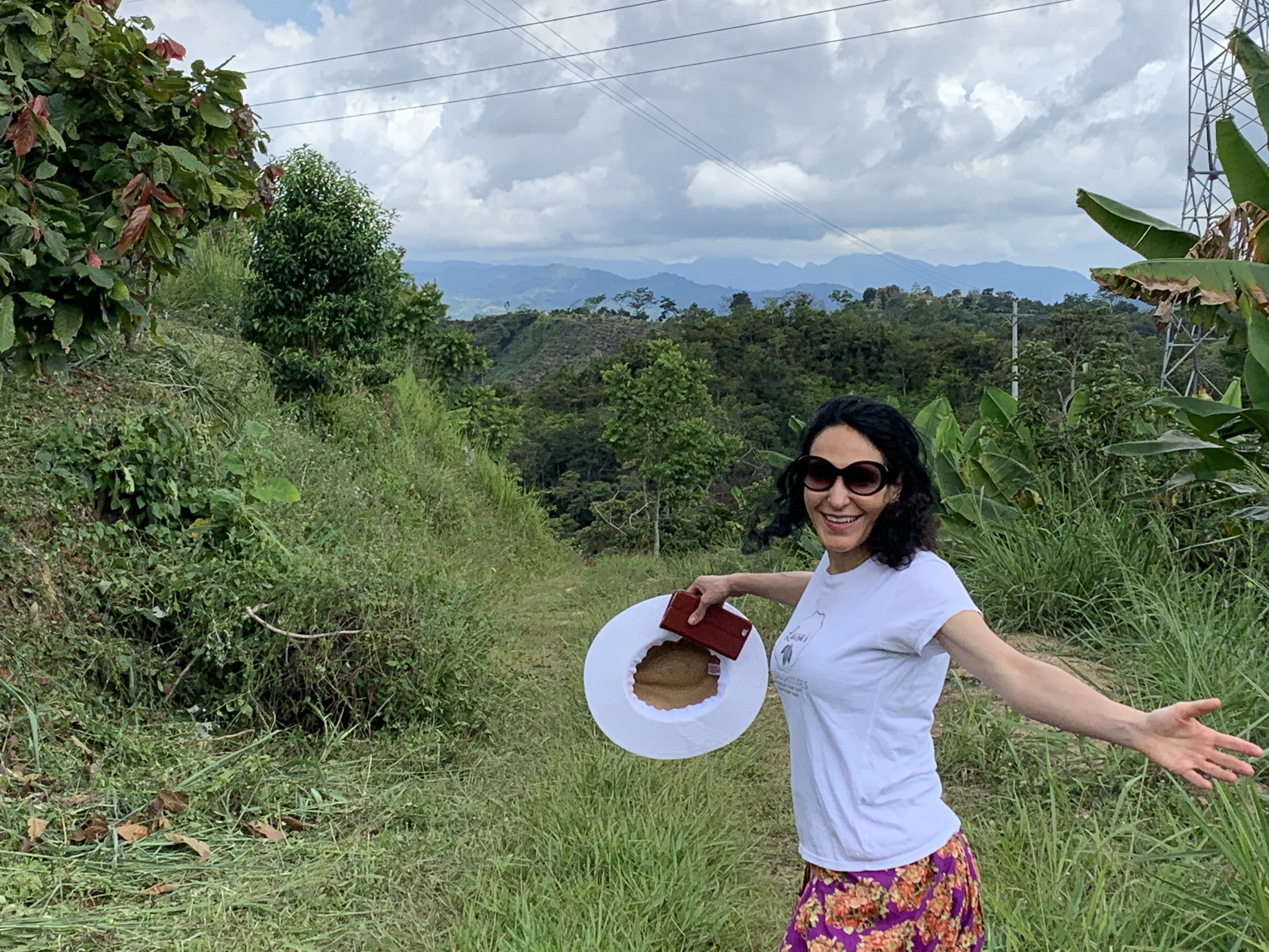 Luisa, with arms outstretched, on a Colombia cacao farm