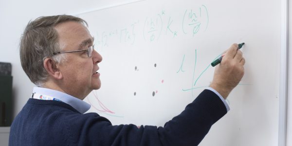 Prof. Murray Lark wearing blue jumper drawing on whiteboard with marker pen