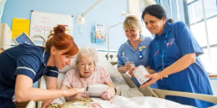 Group of nurses including Liz Charalambous caring for an elderly patient in a hospital bed