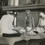Photo depicting Mirabehn and another secretary taking dictation from MK Gandhi in the covered hold of the S.S. Rajputana, which Gandhi used as his quarters