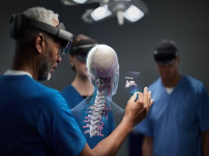 A medical worker wearing a hololens headset looking at a hologram of a human head