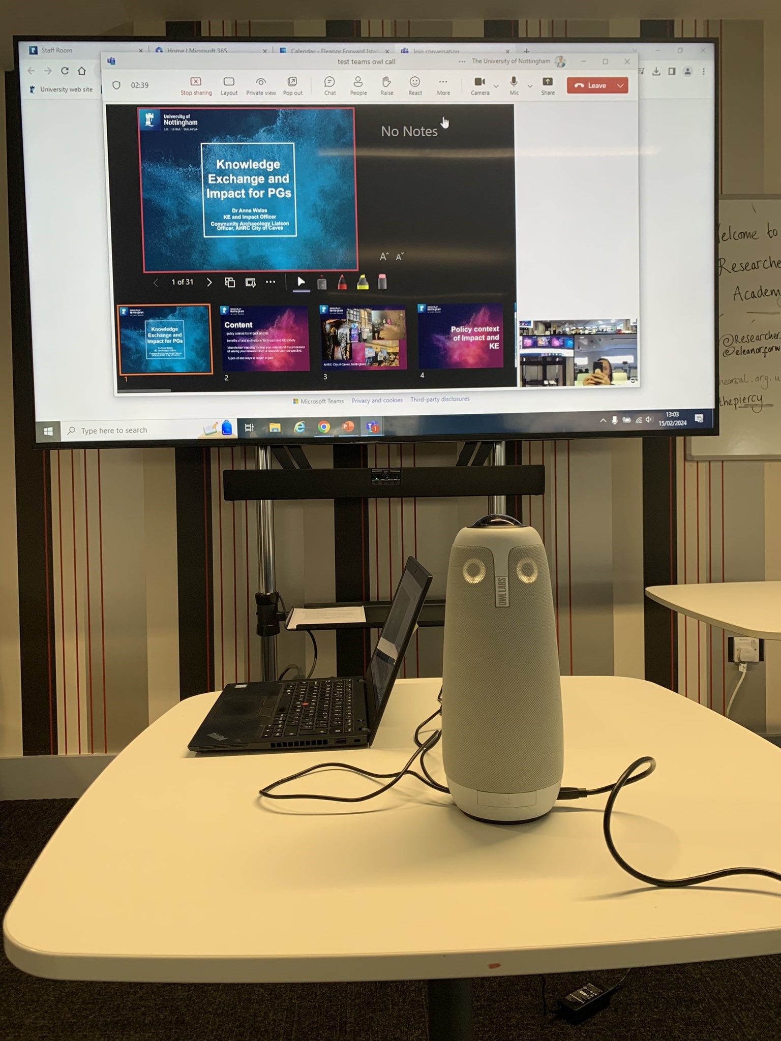 A screen showing a presentation and a table with the OWL on it.