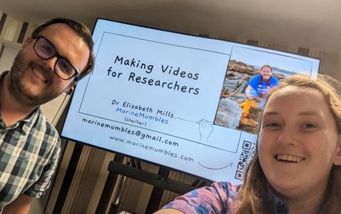 Presenters standing in front of a PowerPoint screen with the title making videos for researchers.