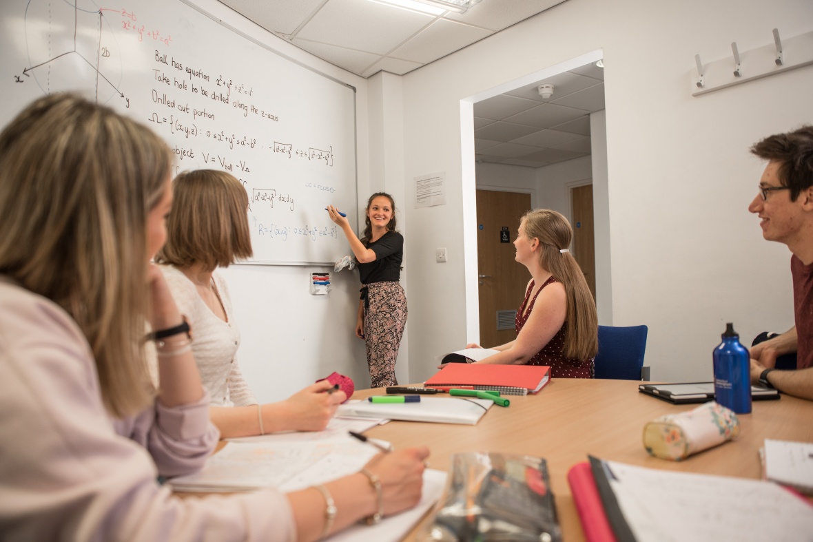 Student pointing at a whiteboard whilst giving a presentation in a seminar