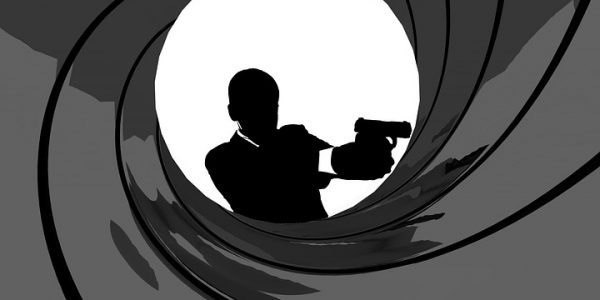 Iconic black and white James Bond image with Bond holding a gun and standing in the middle of a swirling gun barrel