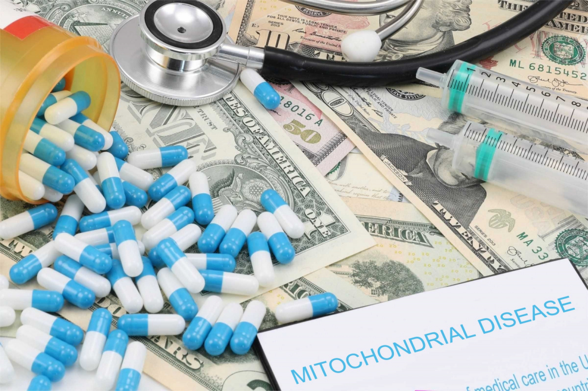 A picture of capsules, syringes and a stethoscope lying on dollar bills together with a note mitochondrial disease written on a pad.
