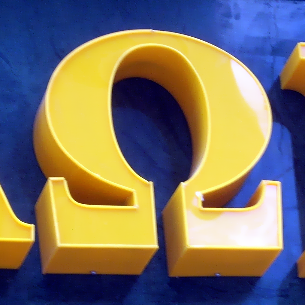 Greek letter omega in yellow plastic on blue background