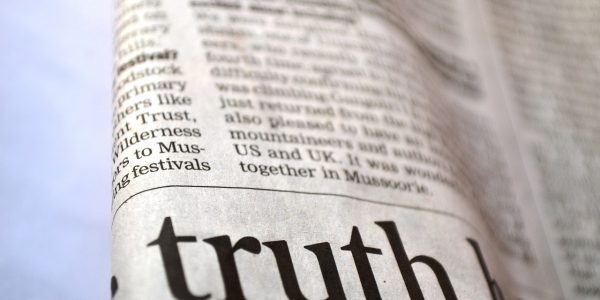 Photo of a folded newspaper with the word truth in pig print