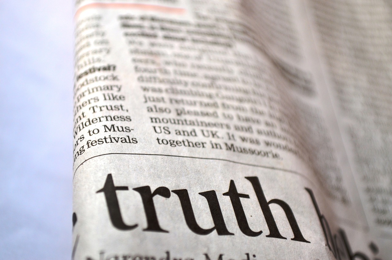Photo of a folded newspaper with the word truth in pig print