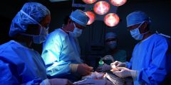 Photo of kidney transplantation, dark operating theatre, blue gowns and masks