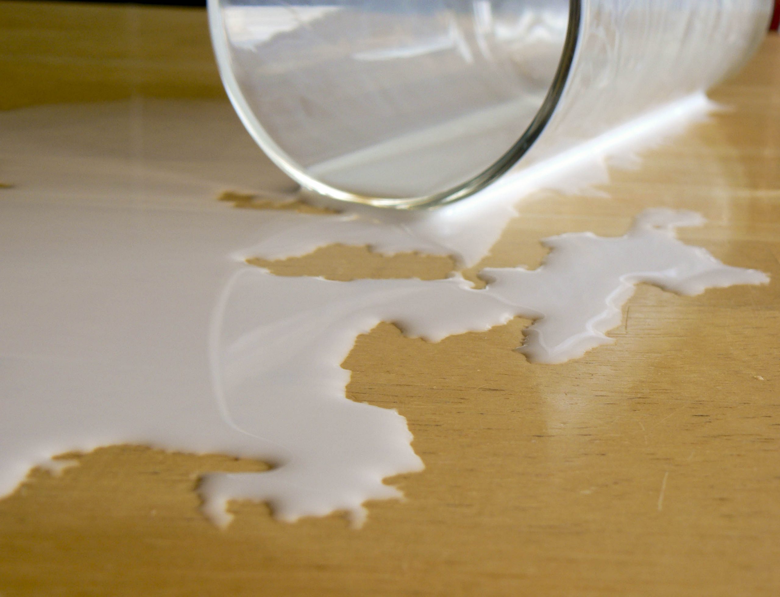 Photo of milk spilt out of glass onto a table
