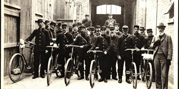 Old black and white photo of postmen on bicycles leaving from Christchurch, NZ, Central Post Office c.1900