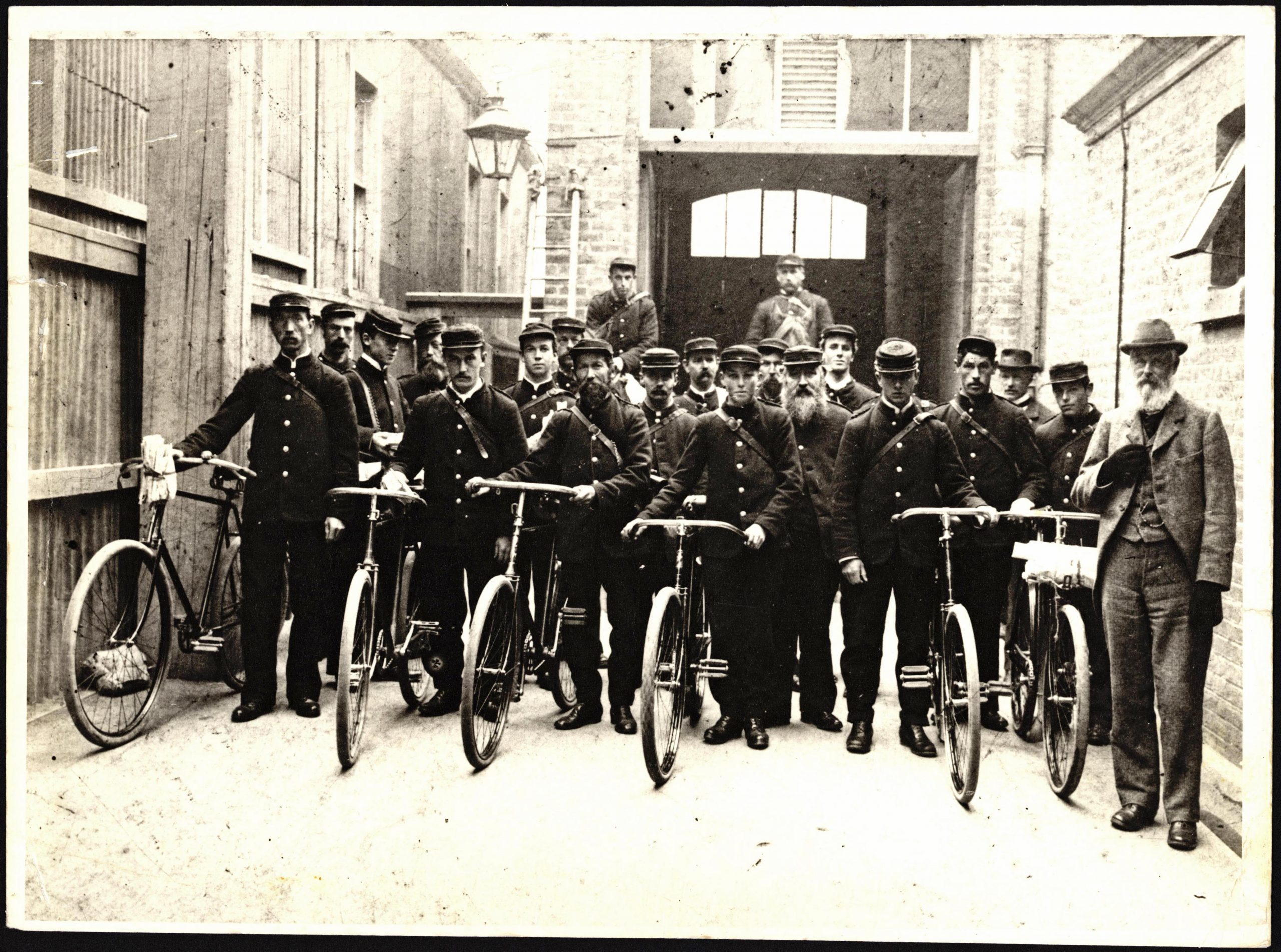 Old black and white photo of postmen on bicycles leaving from Christchurch, NZ, Central Post Office c.1900