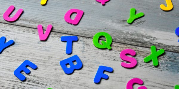 plastic alphabet letters in various colours strewn over a table