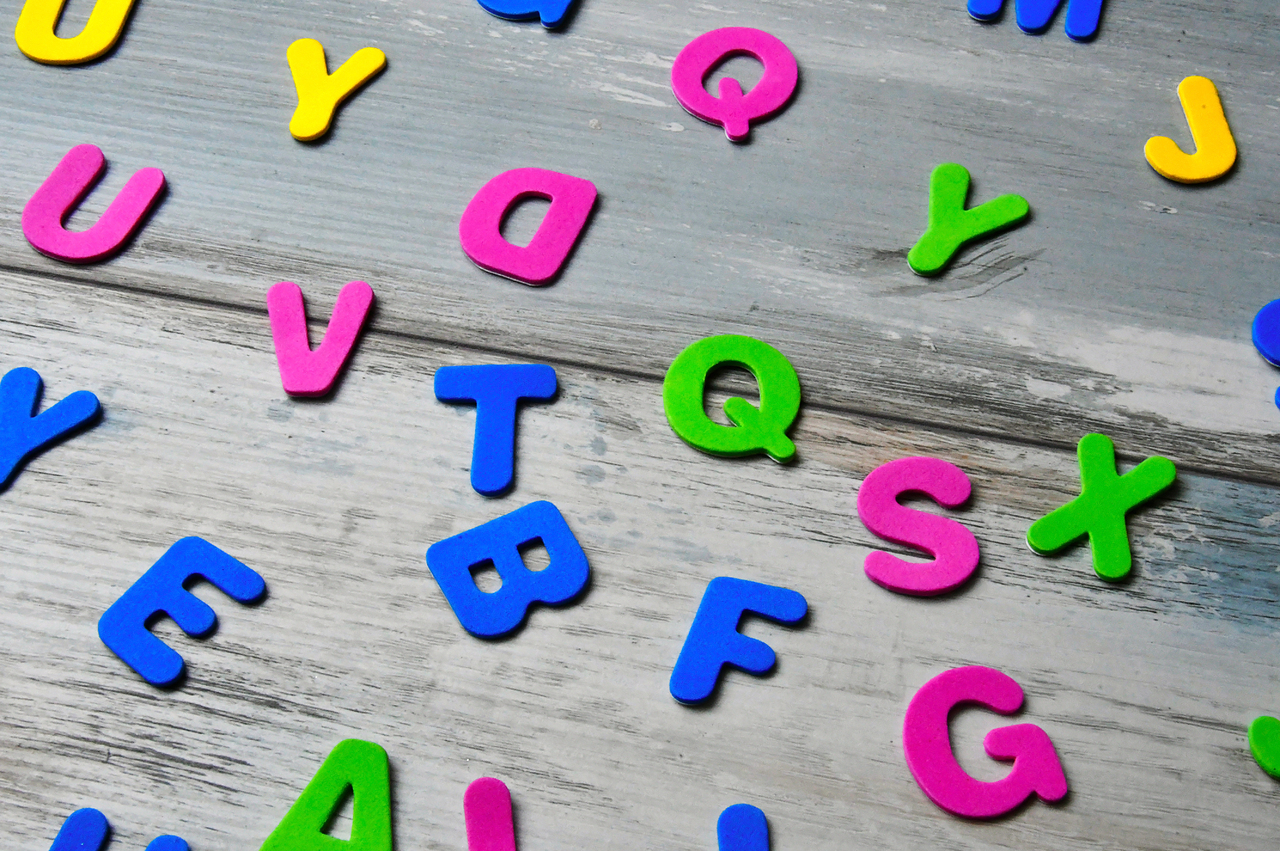 plastic alphabet letters in various colours strewn over a table