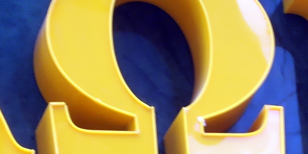 Greek letter omega in yellow plastic on blue background