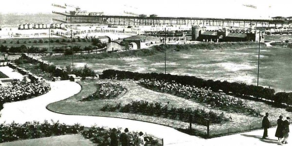 Black and white postcard of the putting green at Skegness, with the pier in the background, c.1938 (Ref: MS 192/117)